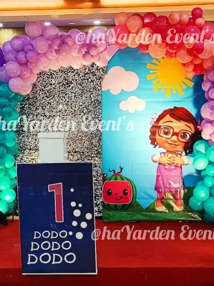 A Cocomelon and Baby Shark crossover theme, perfect for a first birthday. The stage is set with colorful backdrops and balloon columns for a fun-filled celebration.