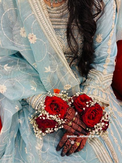 The rich red of the roses in the floral bracelets perfectly matches the deep stain of the henna.