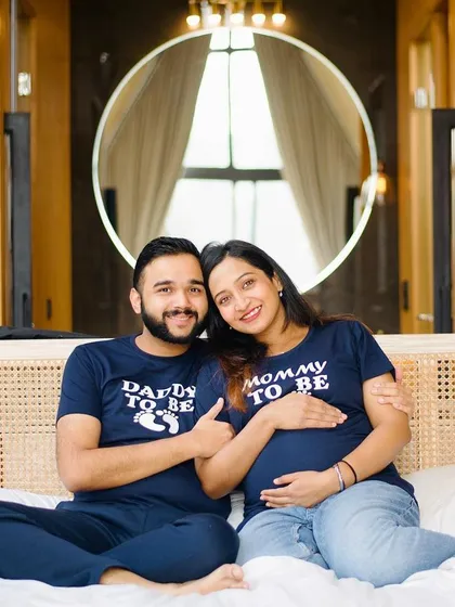 This is a classic pose for a babymoon or indoor couple's shoot. Both parents-to-be are looking at the camera, sharing their happiness. It’s a lovely, straightforward portrait that makes for a perfect keepsake.