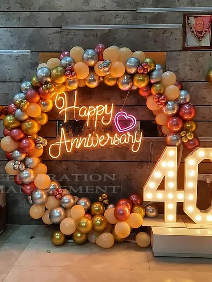 Celebrating a 40th anniversary with an elegant balloon ring in metallic tones, a custom "Happy Anniversary" neon sign, and large marquee numbers.