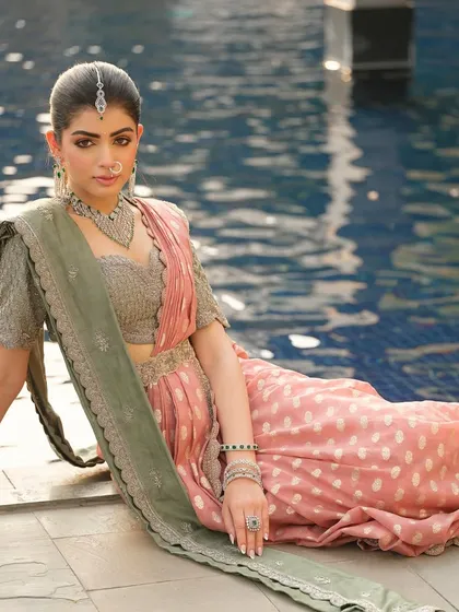 A relaxed pose by the water, showcasing the beautiful texture of the saree and the intricate details of the jewellery.