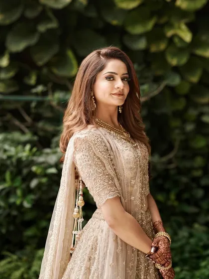 A full view of this gorgeous engagement bride. Her makeup features soft, smokey eyes and a neutral lip, which perfectly complements her intricately detailed golden lehenga and soft curls.