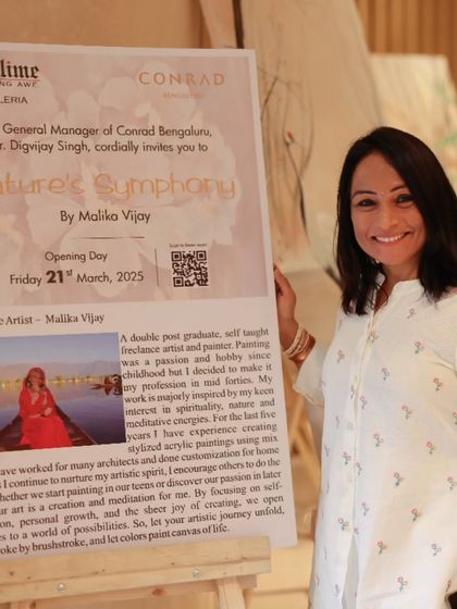 Artist Malika Vijay standing next to the poster for her solo show, 'Nature's Symphony'.