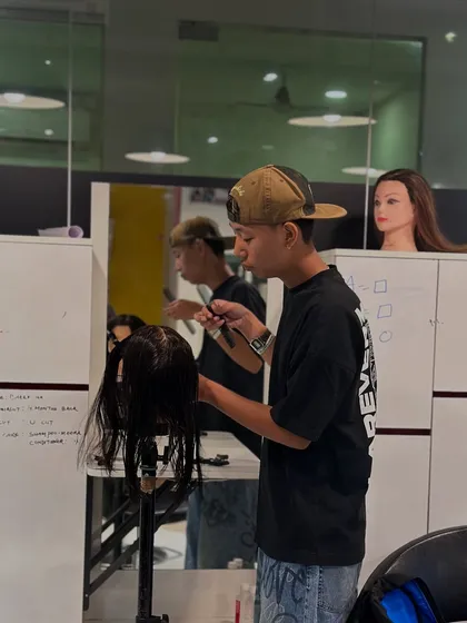 A student fully engaged in his haircutting practice. Our classroom environment is designed for focus and hands-on learning.