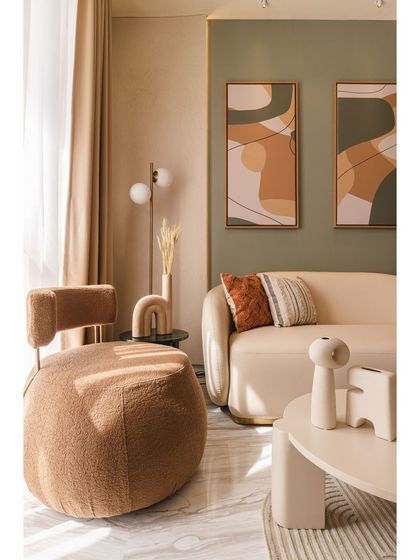 The textured boucle armchair and soft, curved sofa create an inviting seating arrangement. Every piece was chosen to align with the modern Art Deco theme while ensuring the compact space remains comfortable and functional.