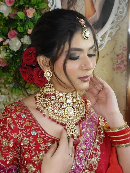 A portrait of the model showcasing the full bridal look, including the stunning red lehenga and heavy kundan jewellery.