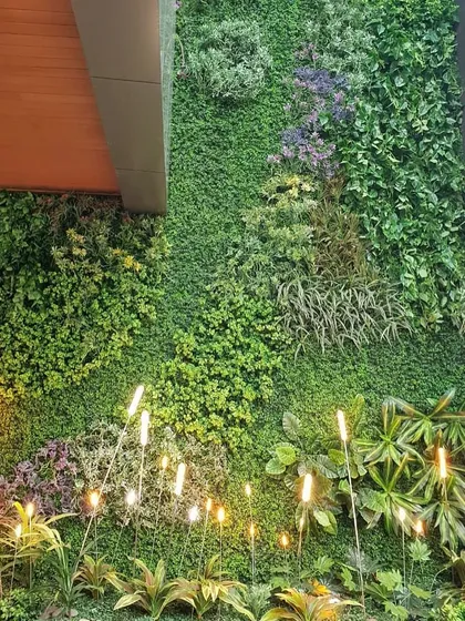 An artificial green wall accented with elegant lighting. This maintenance-free solution is perfect for creating a lush, green ambiance in indoor spaces where conditions are not suitable for live plants.