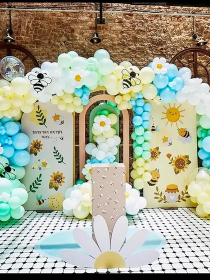 A cheerful 'Happy Bee Day' theme. This elaborate setup uses yellow, blue, and white balloons, with daisy and bee accents, custom backdrops, and a checkered floor to create a buzzing party scene.