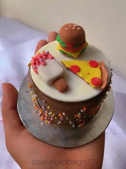 This mini cake proves that calories don't count when it's this cute! It's topped with tiny, hand-sculpted fondant versions of a burger, pizza, and ice cream.
