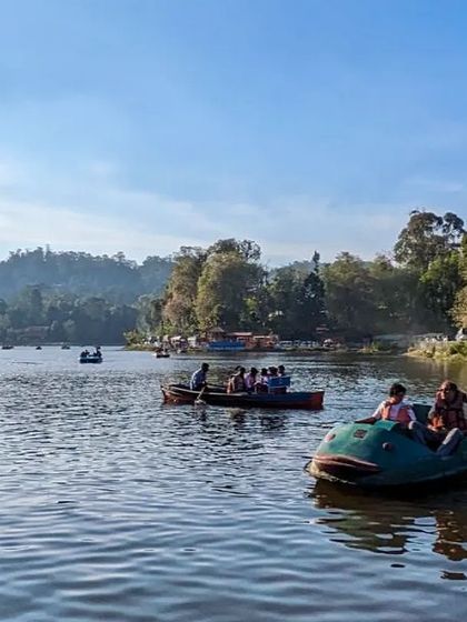 A wide shot of Kodaikanal Lake, filled with colorful pedal boats on a sunny day.