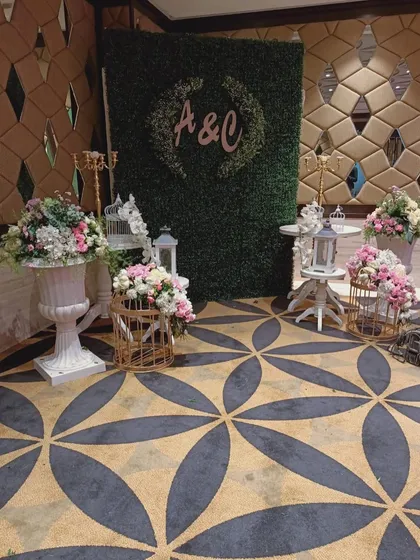 A beautiful floral setup for an engagement party, featuring a hedge wall with the couple's initials, birdcage props, and elegant flower arrangements.