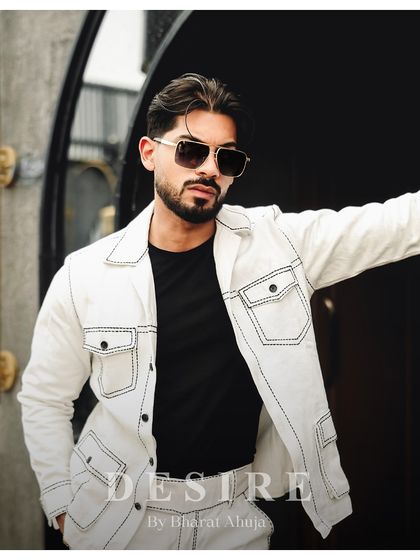 A close-up portrait in the all-white jacket, highlighting its sharp collar and the confident attitude it projects.
