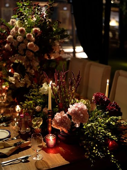 The romantic glow of taper candles and votives interspersed with cascading flowers on the dining table.
