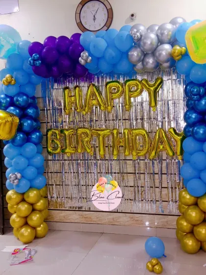 A bold balloon arch in shades of blue and gold with a silver shimmer curtain for a birthday celebration.