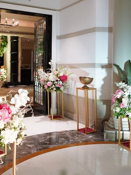 A beautiful decor detail shot, showing floral arrangements on golden pedestals in a grand hotel corridor. This highlights the attention to detail that goes into decorating every part of the venue.