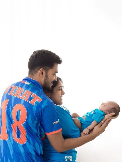 A new family of cricket fans, proudly holding their tiniest team member.