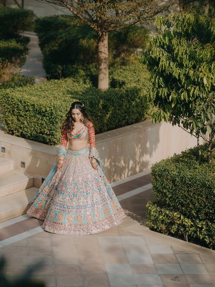A beautiful shot of Chitranksha in her colorful Mehendi lehenga, walking through the lush gardens. This portrait captures the vibrant and joyful spirit of the pre-wedding celebrations.