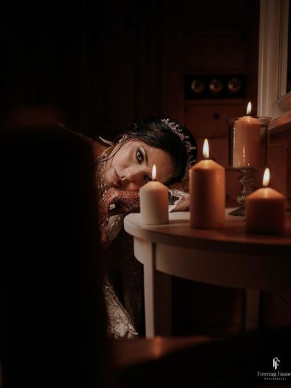 A moody and artistic portrait of the bride by candlelight, her expression full of emotion.