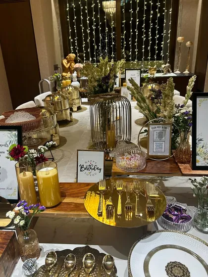 A close-up of a birthday party buffet we catered. The elegant table setting features warm candles, a custom birthday sign, and a beautiful arrangement of our serving dishes, showing our attention to every little detail.