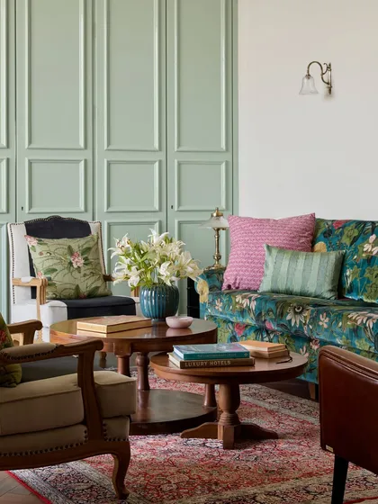 In Mumbai, smart storage is essential. Here, what appears to be a simple mint green paneled wall is actually floor to ceiling storage, seamlessly integrated into the design. I paired this functional element with a bold, floral sofa and eclectic cushions to create a vibrant lounge that is as practical as it is beautiful.