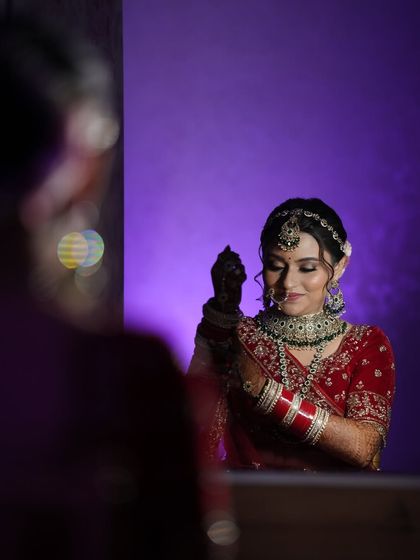 A creative shot of the bride looking in the mirror. This classic pose captures a moment of self-reflection and admiration before the ceremony begins.