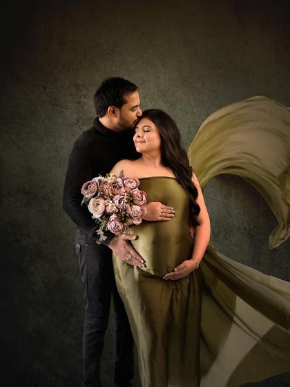 An elegant couple's portrait featuring an olive green fabric drape that adds drama and sophistication.