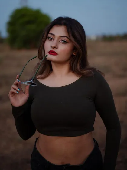 A close-up portrait with a bold red lip and a confident gaze. The outdoor setting and the prop add a touch of attitude to this fashion shot.