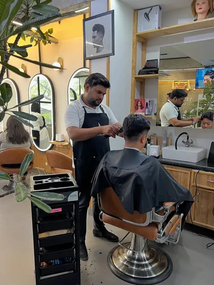 A stylist focusing on a men's haircut, with our modern salon interior in the background.