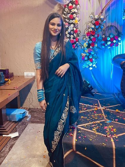 A client at an event wearing the deep teal blue saree, looking effortlessly chic and elegant.