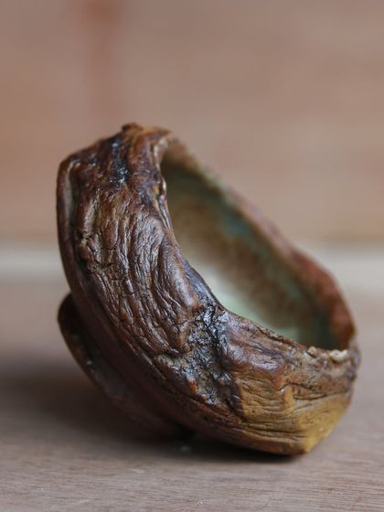 A side view of a textured, hand-built bowl. The organic creases were achieved by pushing and stretching the clay, a technique that embraces imperfection and spontaneity.