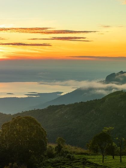The striking Rangaswamy Peak seen from a campsite in Kodanad, Tamil Nadu. The layers of hills are shrouded in morning mist, with the sunrise painting the sky above.