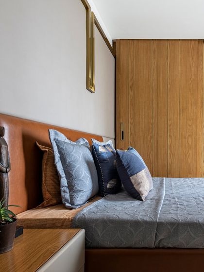 This stylish bedroom from the Filigree House blends comfort with modern aesthetics. The tan leather headboard, cool blue bedding, and warm wood tones create a soothing and elegant ambiance.