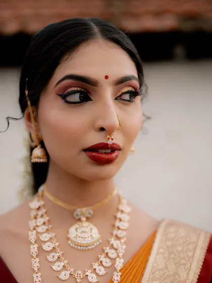 A close-up portrait highlighting the stunning makeup and jewelry of a traditional look. The focus is on the model's expressive eyes and the fine details of her attire.