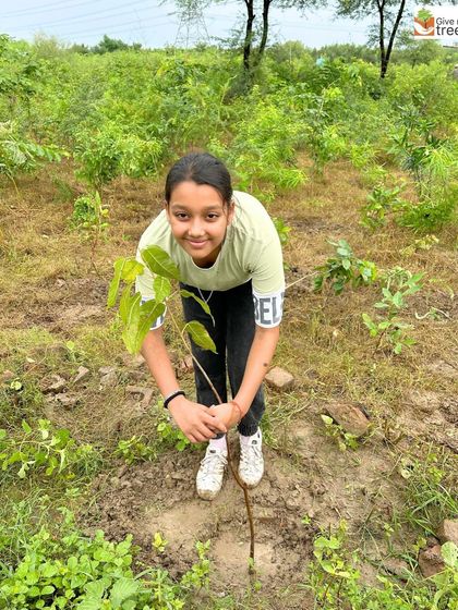 A young girl proudly holds a sapling she is about to plant. We love seeing the next generation take an active role in our community drives.