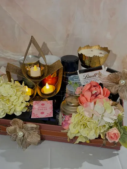 A different view of the Lotus Lit Hamper, highlighting the warm glow of the candles and the beautiful arrangement of flowers and gifts.
