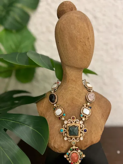 Crafted to turn moments into memories. This navratna-style necklace features a beautiful array of semi-precious stones set in an ornate gold design.