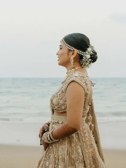 A side profile highlighting the neatness of the floral hair bun and the intricate details of her jewellery.