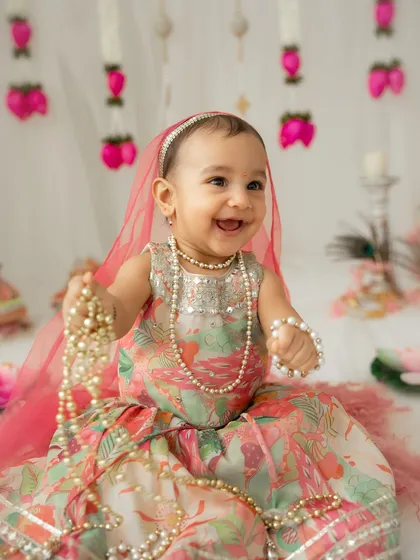 A happy little Radha playing with pearl necklaces. I let babies play and interact with props to capture their natural curiosity and joyful expressions.