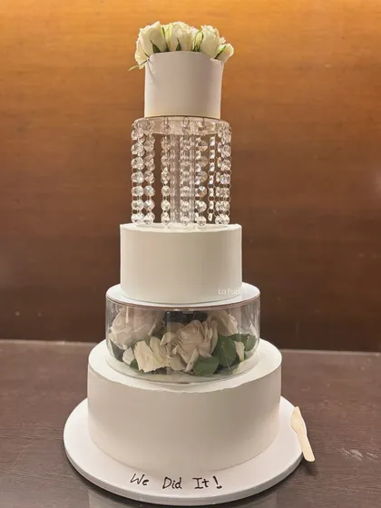 For a touch of pure luxury, this four-tier eggless wedding cake is an absolute showstopper. It features a tier of cascading crystals that sparkle like a chandelier, and another filled with fresh white roses, creating a truly glamorous look.
