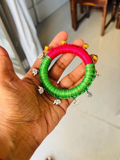 Holding the kids' bangle, you can see the detailed thread wrapping and the securely attached charms. It's all about pura pakka kaam, even for the little ones.