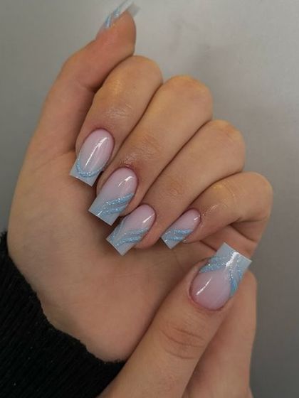 A frosty and elegant design on square nails, with a sheer nude base and abstract swirls of sparkling baby blue glitter.