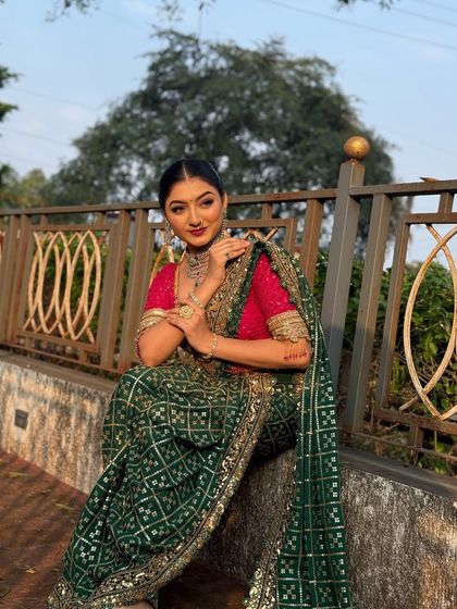 A model in a beautiful green saree. Her hair is styled in a sleek, low bun, a sophisticated choice that highlights her choker necklace.
