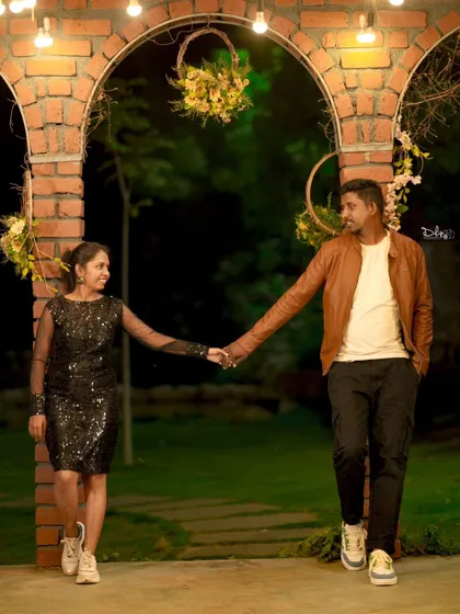 A romantic night-time photo under a brick archway adorned with hanging lights. The warm lighting creates a beautiful, intimate mood.