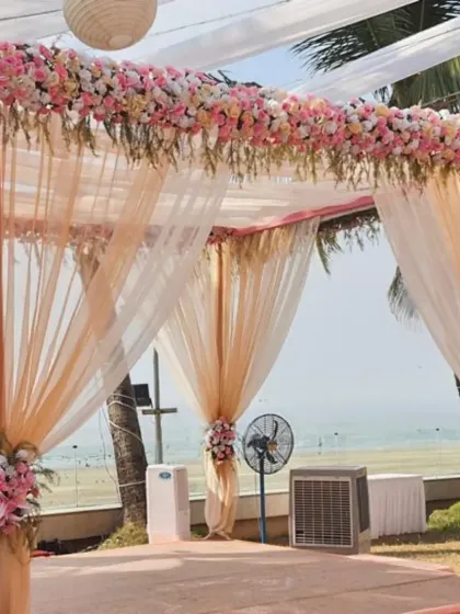 A closer look at a pastel peach and pink mandap. The combination of sheer drapes and thick floral arrangements on the pillars and roof creates a design that is both delicate and grand.