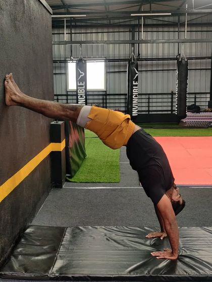 An adult student uses the wall to work on his backbend and shoulder flexibility, a great drill for all levels.
