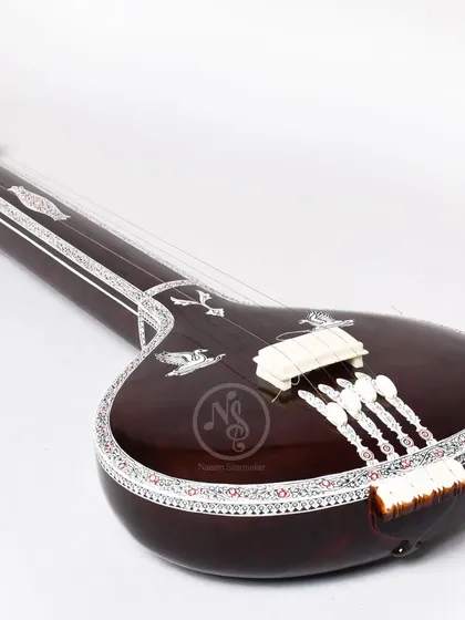 An angled view of the flat wooden tanpuri, highlighting the bridge and the strings. Every part is carefully crafted for the best sound.
