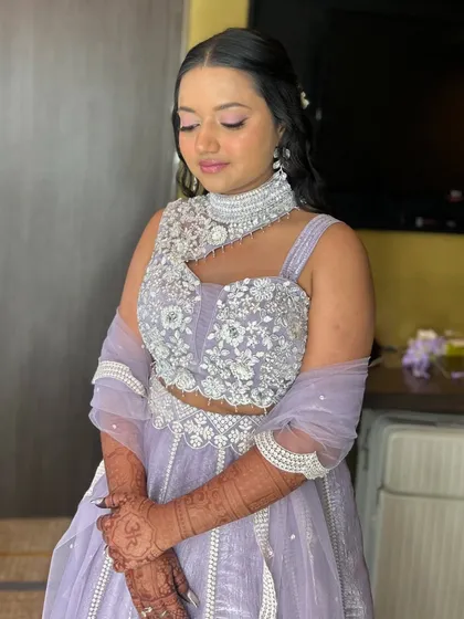 The bride looks serene and beautiful in her lavender lehenga, with her hair styled in soft waves and a delicate braid.