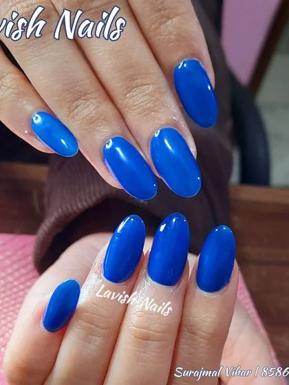 A bold and confident set of solid, glossy royal blue nails in an oval shape.
