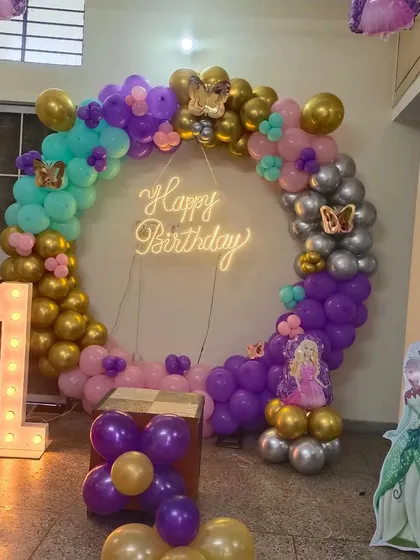 A beautiful butterfly and princess theme for a first birthday. The balloon ring uses purple, gold, and silver colors, with a light-up number '1' and a princess cutout.