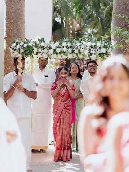 The bride's entrance under a 'phoolon ki chadar' (floral canopy), her expression a mix of anticipation and joy.